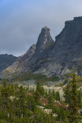 Fototapeta na wymiar rocky ridge under blue sky in mountain valley, journey of climbers on sheer cliffs
