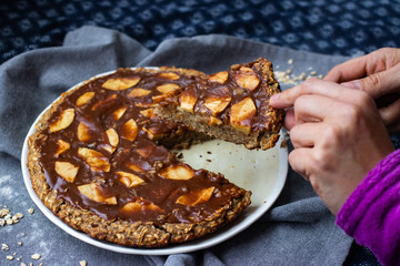 Woman cut chocolate baked apple, fruit, oatmeal and nuts brownie with dip cream spread. Sweet vegan brown dessert cake, pie. 