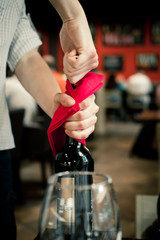 The waiter opens a bottle of wine with a corkscrew