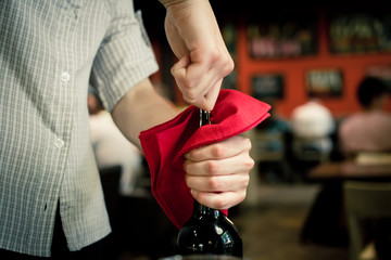 The waiter opens a bottle of wine with a corkscrew