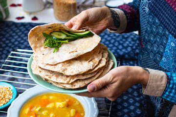 Plain chapati or tortillas flatbread. Naan bread with vegetables salad. Vegan food. Woman hands