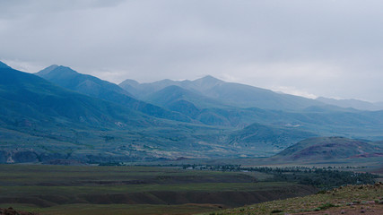 mountain valley under cloudy sky, rock ridge on horizon, hiking in  mountains, rest and meditation in nature