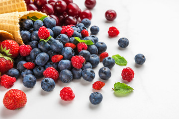 Blueberries, raspberries, strawberries and cherry berries in waffle ice cream cones on white