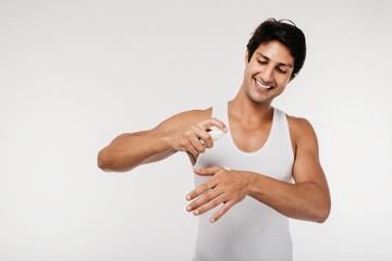 Portrait of handsome man applying cream skin care on his face, looking at camera and smiling...