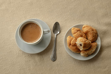 Closeup of coffee white cup croissants on white background for lifestyle design. Morning relaxation. Hot drink.