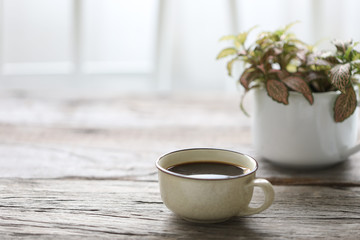 Coffee in vintage cup and plant on wooden table