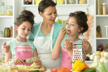 Family preparing delicious fresh salad in kitchen