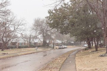 Heavy snowfall over suburban residential street with row of bungalow houses and sidewalk in Coppell, Texas, USA