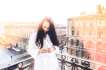 Young woman on vacation. Woman on the balcony with champagne. Photo of a girl on a balcony in St. Petersburg in the sun.