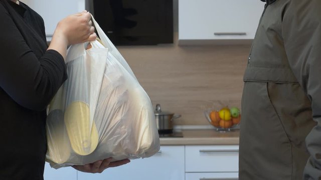 A courier in rubber gloves passes the girl food in a plastic bag. Taken at home