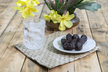 Dates and ice water on the wooden table and selective focus