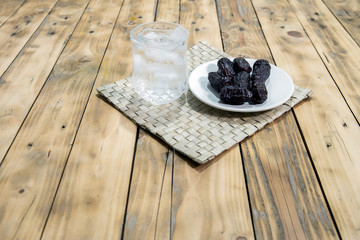 Dates and ice water on the wooden table and selective focus