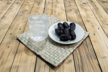 Dates and ice water on the wooden table and selective focus