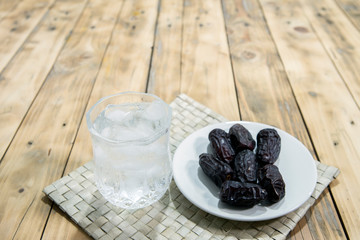Dates and ice water on the wooden table and selective focus