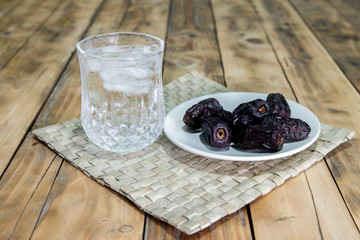 Dates and ice water on the wooden table and selective focus