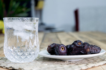 Dates and ice water on the wooden table and selective focus