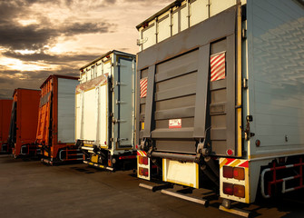 trucks with lift door packing at sunset sky, road freight shipping cargo, logistics and transport