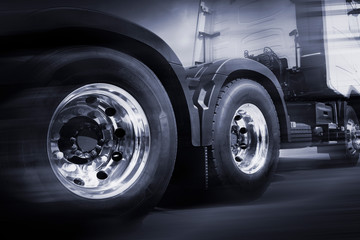 semi truck speeding, close up truck wheels, road freight transport and logistics.