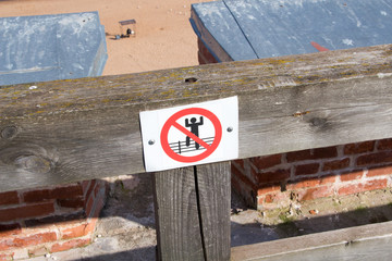 Warning sign on a wooden railing