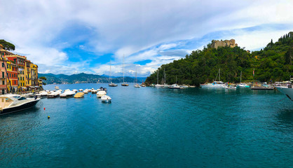 Naklejka premium Wide panoramic view of Portofino, one of the world's most beautiful seaside towns on the Italian Riviera. Mediterranean landscape of yacht-filled harbor. ITALY - June, 2018.