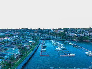 Fototapeta na wymiar Panoramic drone aerial view over Sydney harbour on a cloudy sunset showing the nice colours of the harbour foreshore