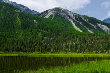 lake in mountain valley, surface of water under rocky peaks, mountain surface on horizon, path to top and its achievement by  river