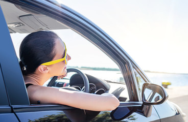 Girl drives a car on a sunny day.