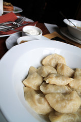 Dumplings with cottage cheese in a white plate with sour cream