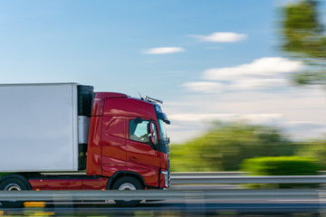 Truck with refrigerated semi-trailer driving on the highway with a blue sky with some clouds