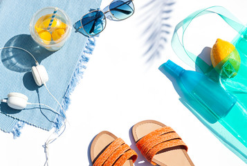 Bright summer beach vacation or travel lifestyle concept flat lay with lemonade, a, sunglasses and sunscreen spray. Top view. Copy space