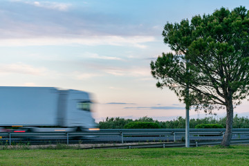 Truck with refrigerated semi-trailer moving on the highway at sunset