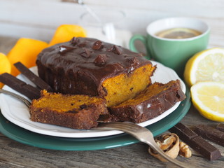 Festive homemade chocolate pumpkin long rectangular cupcake glazed with chocolate. Wooden table.