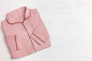 Pink or red pajamas with striped on white wooden surface with copy space. Night suit for sleeping....