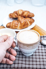 Men's hands with a cup of coffee. Homemade breakfast with coffee and croissants.