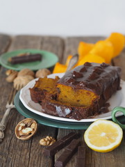 Festive homemade chocolate pumpkin long rectangular cupcake glazed with chocolate. Wooden table.