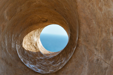 Sea view through the stone hole. Watch blue sky and sea through the stone spiral tunnel in Cyprus