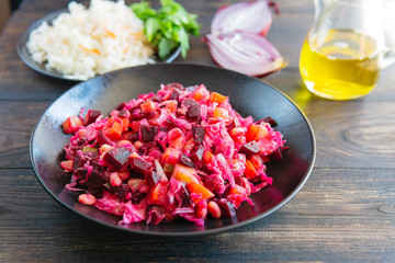 Vinegret or vinaigrette,  red beet salad with cooked and pickled vegetables, oil, onion, herbs, beetroot. Vegan healthy food. Dietary menu.  Organic food, wooden rustic table.