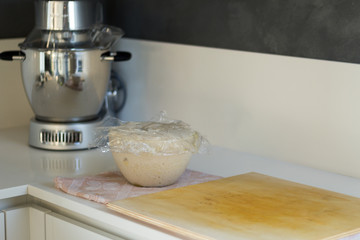 dough for bread and pizza while rising in the bowl near the mixer