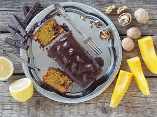 Festive homemade chocolate pumpkin long rectangular cupcake glazed with chocolate. Wooden table.