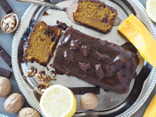 Festive homemade chocolate pumpkin long rectangular cupcake glazed with chocolate. Wooden table.