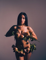 Young and sexy naked woman with rose flowers instead of underwear.