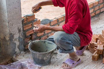 Construction worker placing bricks on cement for building exterior walls