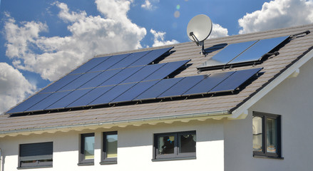 Neue Solaranlage auf dem schwarzen Ziegeldach eines moderen Einfamilien-Neubauhauses