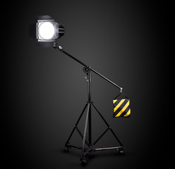 Photography studio flash on a lighting stand isolated on black background.