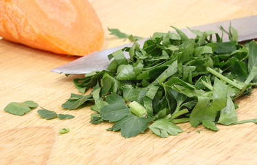 Fresh green parsley on a background of a knife blade and orange carrots