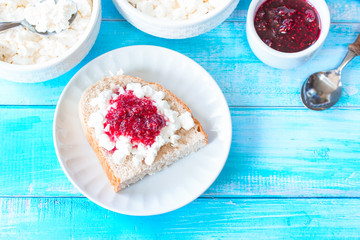 sandwich with cottage cheese and raspberry jam in a plate top view. bowls with cottage cheese, jam and a sandwich with cottage cheese and jam close-up.