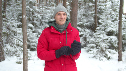 A man in a snowy forest puts on winter gloves