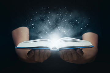 Man open magic book with growing lights and magic powder floating on the book, Learning, Education,...