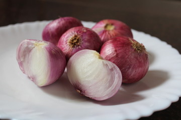Whole and sliced onion on a plate.