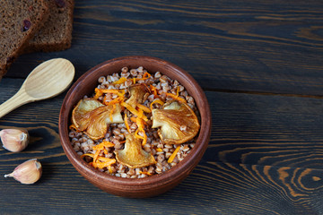 Buckwheat porridge with mushrooms in a ceramic bowl on a dark wooden rustic background